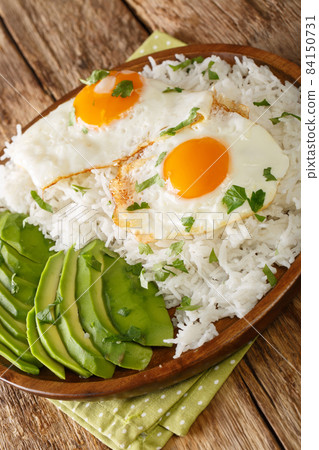 Arroz con huevo or rice with fried egg is the ultimate Latin lazy lunch close up in the plate. Vertical Arroz con huevo or rice with fried egg is the ultimate Latin lazy lunch close up in the plate. Vertical 84150731