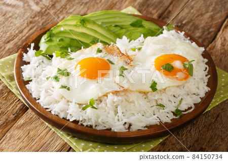 Arroz con huevo is a popular lazy lunch throughout Latin America, consisting of rice thats topped with a fried egg close up in the plate. Horizontal 84150734
