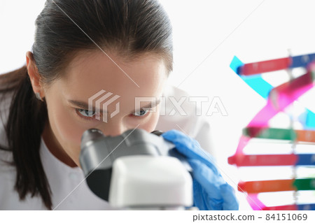 Woman scientist looking through a microscope, studying dna Woman scientist looking through a microscope, studying dna 84151069