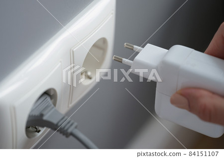 Hand inserts laptop power supply into the socket Hand inserts laptop power supply into the socket 84151107