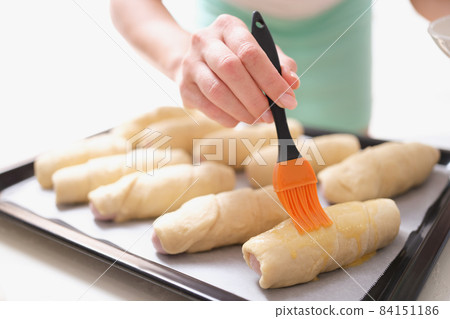 A woman before baking with a brush lubricates dough products A woman before baking with a brush lubricates dough products 84151186