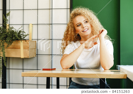 Casual young attractive woman sitting at the table in cafeteria and waiting for her order 84151263