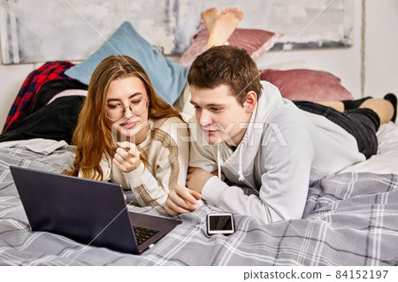 Online shopping of married couple lying on bed in bedroom in front of laptop screens. Online shopping of married couple lying on bed in bedroom in front of laptop screens. 84152197