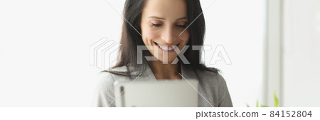 Smiling young woman in suit holding digital tablet 84152804