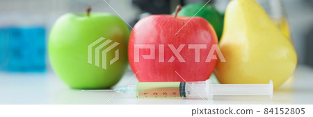 Apples and pear lying on table in laboratory near syringe with medicine closeup 84152805