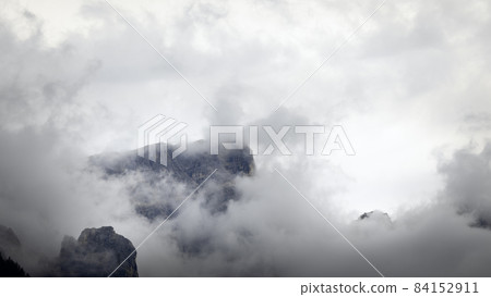 View of the mountain top of the Italian Dolomites through low clouds and fog 84152911