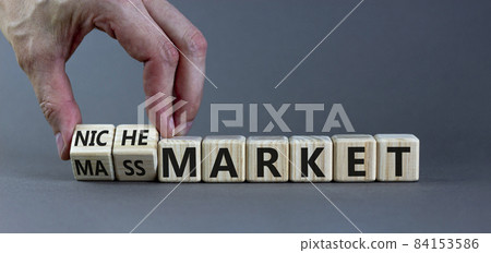 Mass or niche market symbol. Businessman flips wooden cubes and changes words 'mass market' to 'niche market'. Beautiful grey background, copy space. Business and mass or niche market concept. 84153586