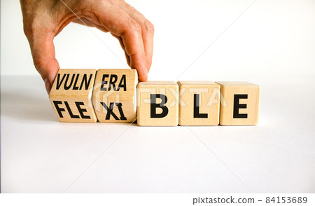 Vulnerable or flexible symbol. Businessman turns wooden cubes and changes words 'vulnerable' to 'flexible'. Beautiful white background, copy space. Business, vulnerable or flexible concept. Vulnerable or flexible symbol. Businessman turns wooden cubes and changes words 'vulnerable' to 'flexible'. Beautiful white background, copy space. Business, vulnerable or flexible concept. 84153689