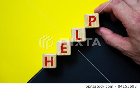Support and help symbol. Wooden cubes with the word 'help'. Businessman hand. Business, psychology, support and help concept. Beautiful yellow and black background, copy space. 84153698