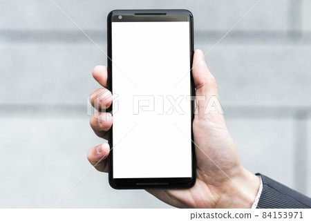 businessperson s hand showing white display screen smartphone against blurred backdrop. High quality beautiful photo concept 84153971
