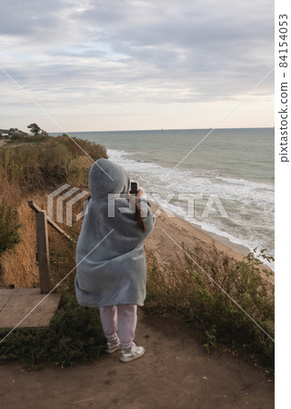 Young woman on cold autumn seashore posing at camera 84154053