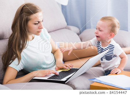 Mother is working on laptop while child naughty Mother is working on laptop while child naughty 84154447