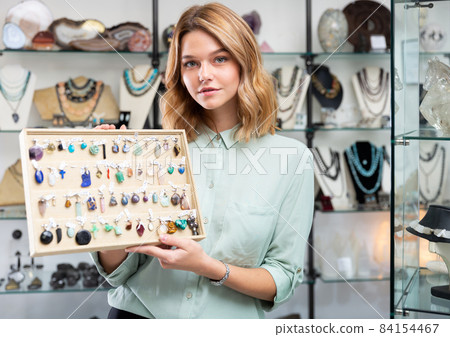 Saleswoman showing pendants from natural gemstones Saleswoman showing pendants from natural gemstones 84154467