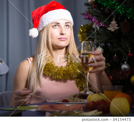 Sad woman is bored with champagne in New Year night Sad woman is bored with champagne in New Year night 84154473