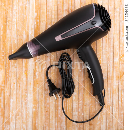 Black blow dryer on wooden surface Black blow dryer on wooden surface 84154688