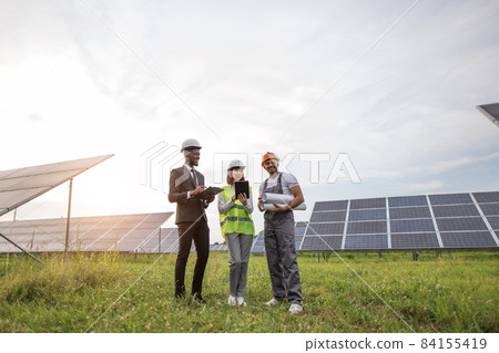 Indian technician standing at solar farm with two inspectors Indian technician standing at solar farm with two inspectors 84155419
