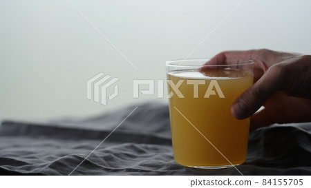 man hand take orange soft drink in tumbler glass from linen cloth man hand take orange soft drink in tumbler glass from linen cloth 84155705