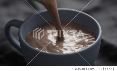 pour hot chocolate into blue cup closeup 84155721