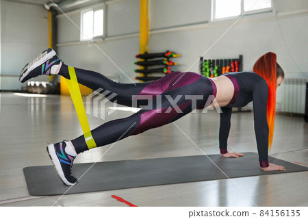 Athletic woman goes in for sports with a rubber band on legs. 84156135