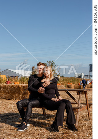 Young couple sitting on the farm. Happy young couple in love sitting and looking at camera. Autumn time. Young couple sitting on the farm. Happy young couple in love sitting and looking at camera. Autumn time. 84156939
