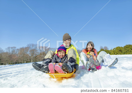 A family of four playing in a snowy park 84160781