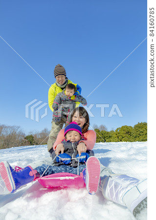 A family of four playing in a snowy park 84160785