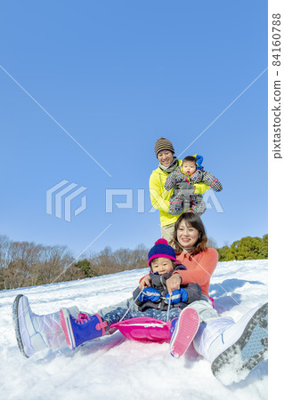 A family of four playing in a snowy park 84160788