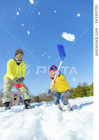 A family of four playing in a snowy park 84160791