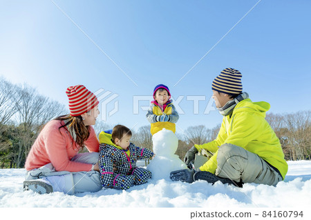 A family of four playing in a snowy park 84160794