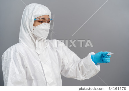 doctor in PPE suit looking temperature at digital thermometer doctor in PPE suit looking temperature at digital thermometer 84161378