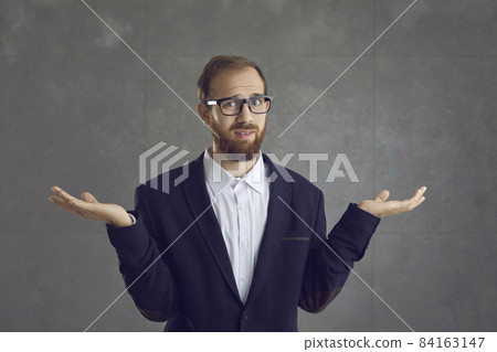Irritated adult caucasian businessman with displeased face expression in formal suit showing so what or dont know gesture studio headshot. Confused man shrugging up looking at camera portrait Irritated adult caucasian businessman with displeased face expression in formal suit showing so what or dont know gesture studio headshot. Confused man shrugging up looking at camera portrait 84163147