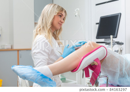 A gynecologist conducts a routine examination of a girl on a gynecological chair using modern medical technologies 84163297