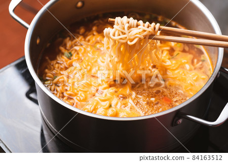 Asian spicy instant noodles soup cooking in hot pot with chopsticks 84163512