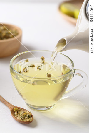 Chamomile tea in a teapot pouring into cup glass, Healthy herbal tea 84163564