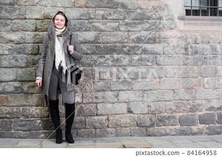 teenager girl in hood near wall 84164958
