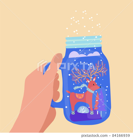 hand holding mason jar with winter landscape and deer 84166939