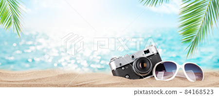 Retro camera and sunglasses on tropical beach 84168523