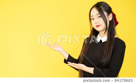 Pointing woman. Promotion banner. Content advertising. Discount offer. Cute young girl demonstrating yellow empty space recommendation background. Pointing woman. Promotion banner. Content advertising. Discount offer. Cute young girl demonstrating yellow empty space recommendation background. 84170683