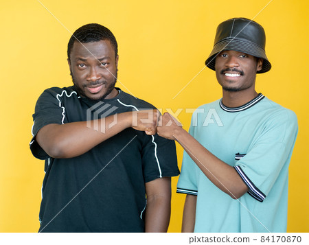Fist bump. Male friendship. Team collaboration. Happy hipster men meeting hands together supportive each other isolated yellow. Fist bump. Male friendship. Team collaboration. Happy hipster men meeting hands together supportive each other isolated yellow. 84170870