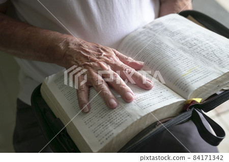 Hand of a senior man on an open book. Hand of a senior man on an open book. 84171342