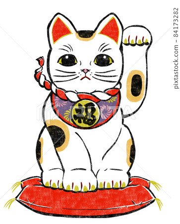 A calico beckoning cat sitting on a cushion and raising his left leg. 84173282