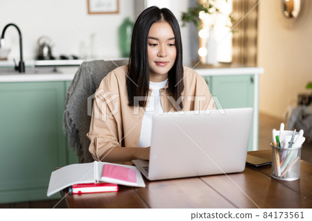 Asian girl studying at home, distance education concept. Female student learning with laptop. Young woman working remote, sitting in kitchen with books and computer 84173561