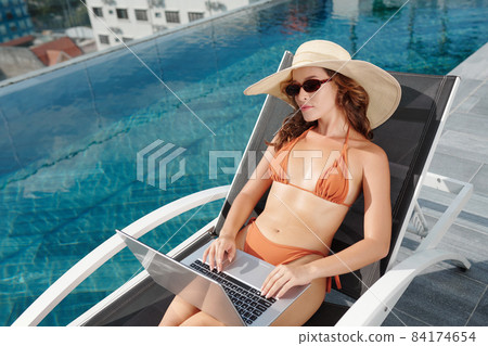 Woman Sitting by Swimming Pool 84174654