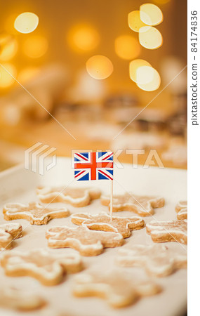 British holiday and Christmas baking concept. Union Jack flag of Great Britain and gingerbread men biscuits in the kitchen in England British holiday and Christmas baking concept. Union Jack flag of Great Britain and gingerbread men biscuits in the kitchen in England 84174836