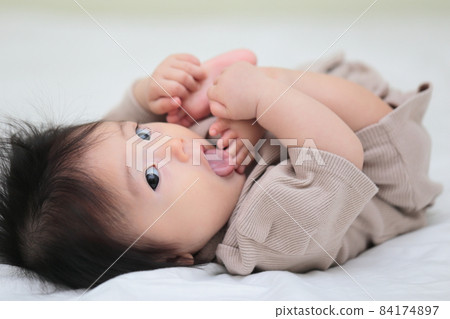 Half-year-old baby licking his feet 84174897
