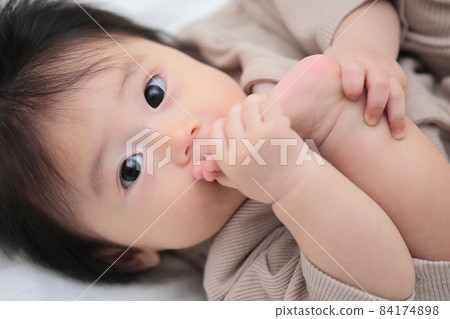 Half-year-old baby licking his feet 84174898