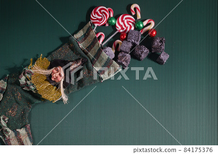 Befana sock with sweet coal and candy on dark greeen background. Italian Epiphany day tradition. Befana sock with sweet coal and candy on dark greeen background. Italian Epiphany day tradition. 84175376