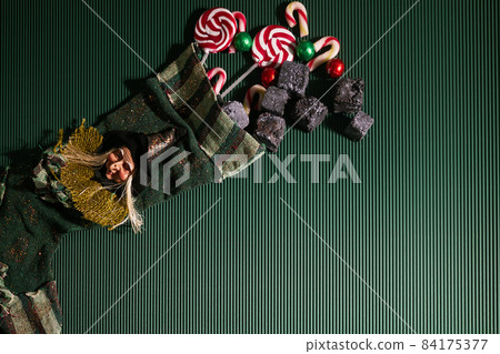 Befana sock with sweet coal and candy on dark greeen background. Italian Epiphany day tradition. Befana sock with sweet coal and candy on dark greeen background. Italian Epiphany day tradition. 84175377