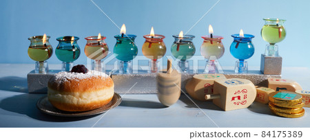 Jewish holiday Hanukkah background with oil Menorah- traditional candelabra, spinning top Dreidel and Doughnut on blue background 84175389