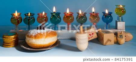 Jewish holiday Hanukkah background with oil Menorah- traditional candelabra, spinning top Dreidel and Doughnut on blue background 84175391